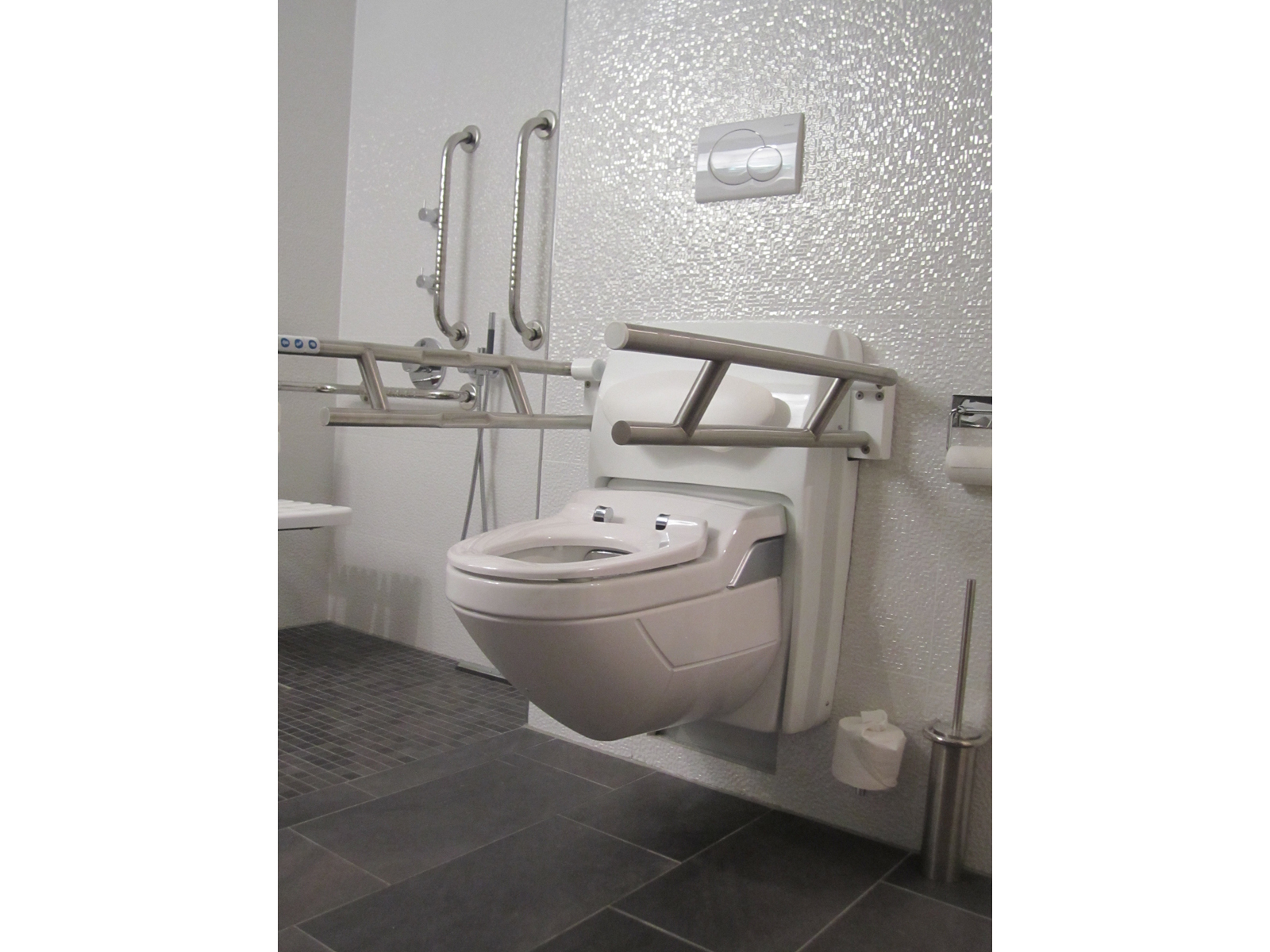 Lift Toilette CarePlus. Elektrisch höhen- und neigungsverstellbare Lift Toilette mit Stütz-Klapp-Griffen.