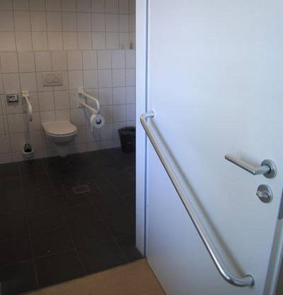 Barrierefreies Bad: Die Tür schlägt nach außen auf und ist mit einer Stange versehen, damit Rollstuhlnutzer die Tür besser schließen können.