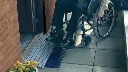 Rollstuhlfahrer vor einem mobilen Rampenset mit Baukastenstecksystem, das nach drinnen führt. (Bild Kvistberga_Volaris)