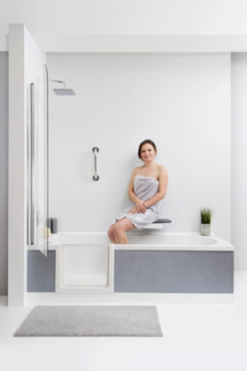 Eine Person sitzend beim Duschen in einer Badewanne mit Tür.