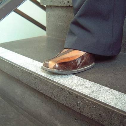 Ein Fuß steht auf einer Treppenstufe mit selbstklebenden Anti-Rutschbelägen.