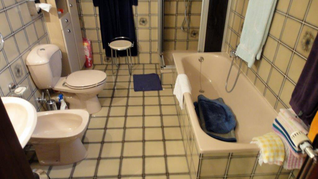 Älteres Badezimmer mit Badewanne, Stand-WC, Bidet und Waschbecken.