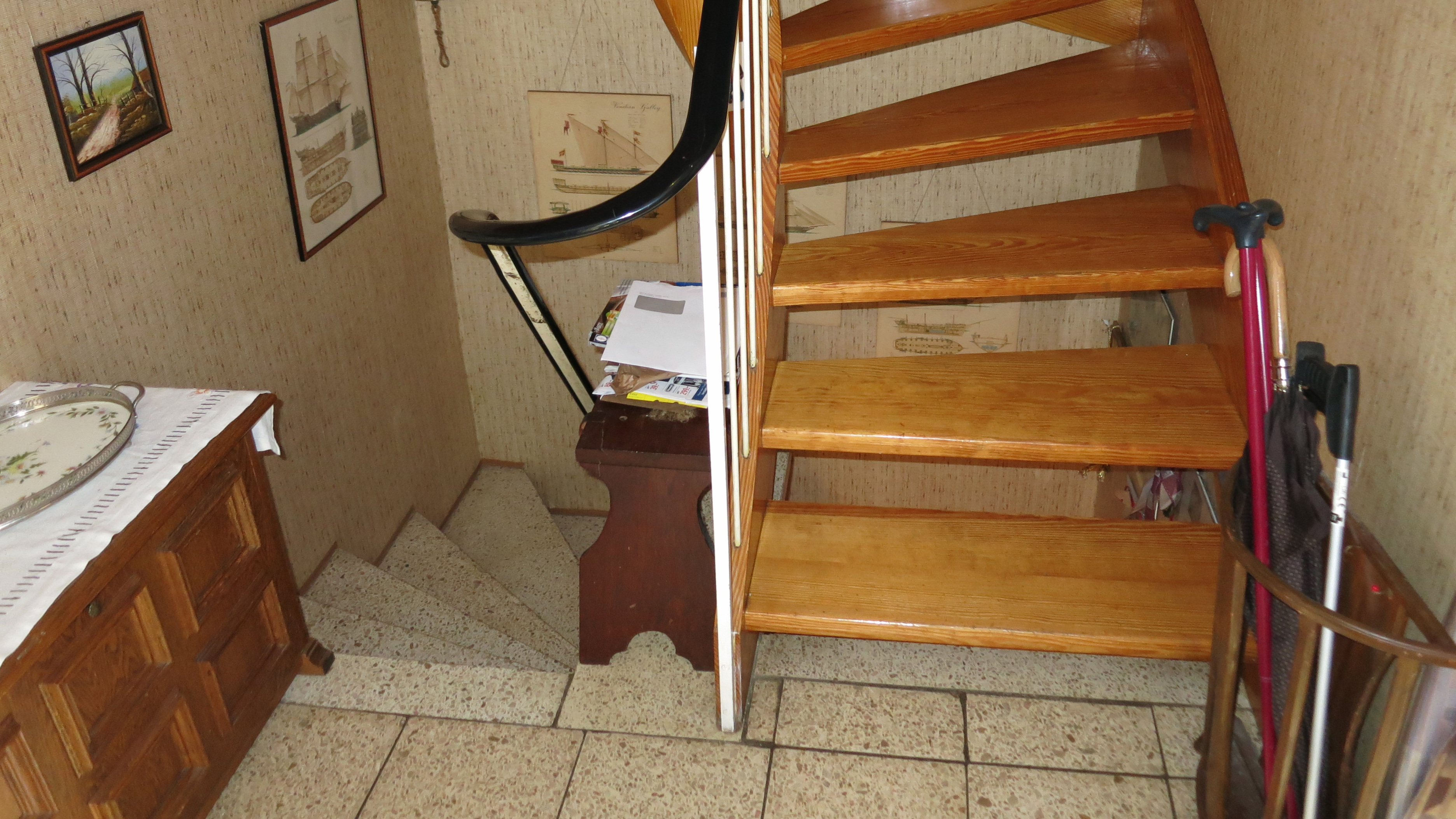 Eine Treppe in den Keller und direkt daneben eine Treppe ins Oberschoss. Im Vordergrund ein Gehhilfenstock.