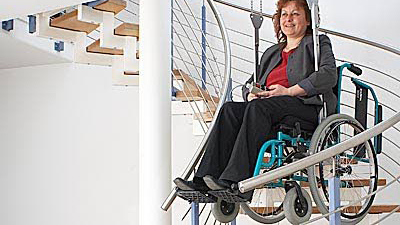 Rollstuhlfahrerin an einem, an der Decke befestigten, Treppenlift