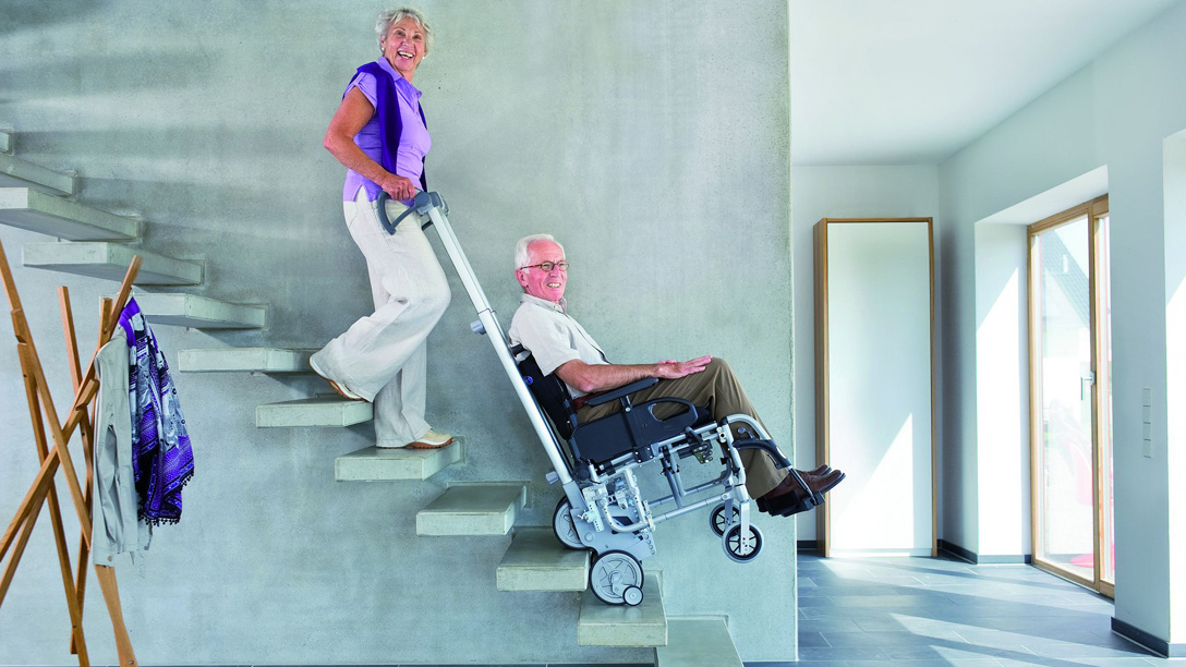 Rollstuhlfahrer und Begleitperson testen eine Treppensteighilfe (Fa. Alber GmbH)