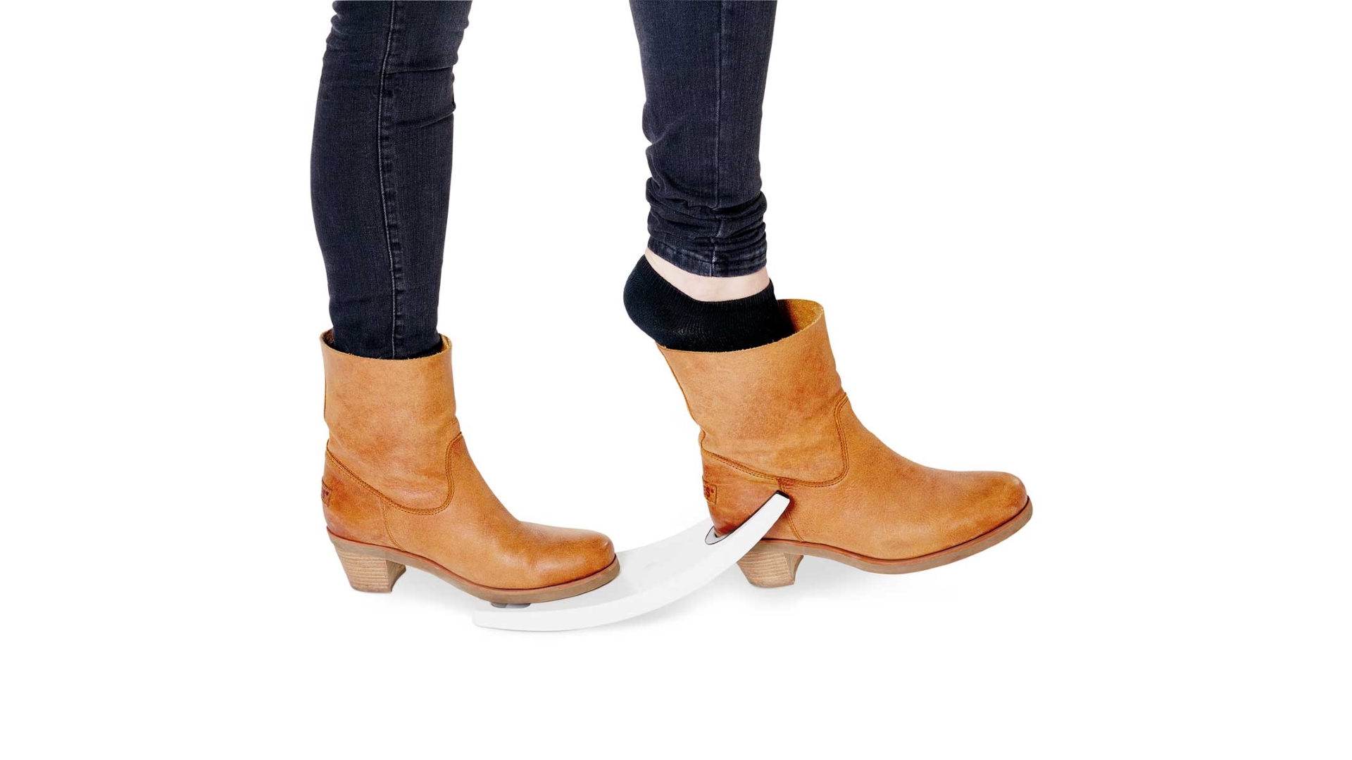 Abbildung zweier Füße mit Damenstiefeln, ein Fuß steht auf dem flachen Teil des Schuhausziehers, der andere Stiefel ist im vorderen Ausschnitt eingeklemmt und der Fuß kann herausgezogen werden.