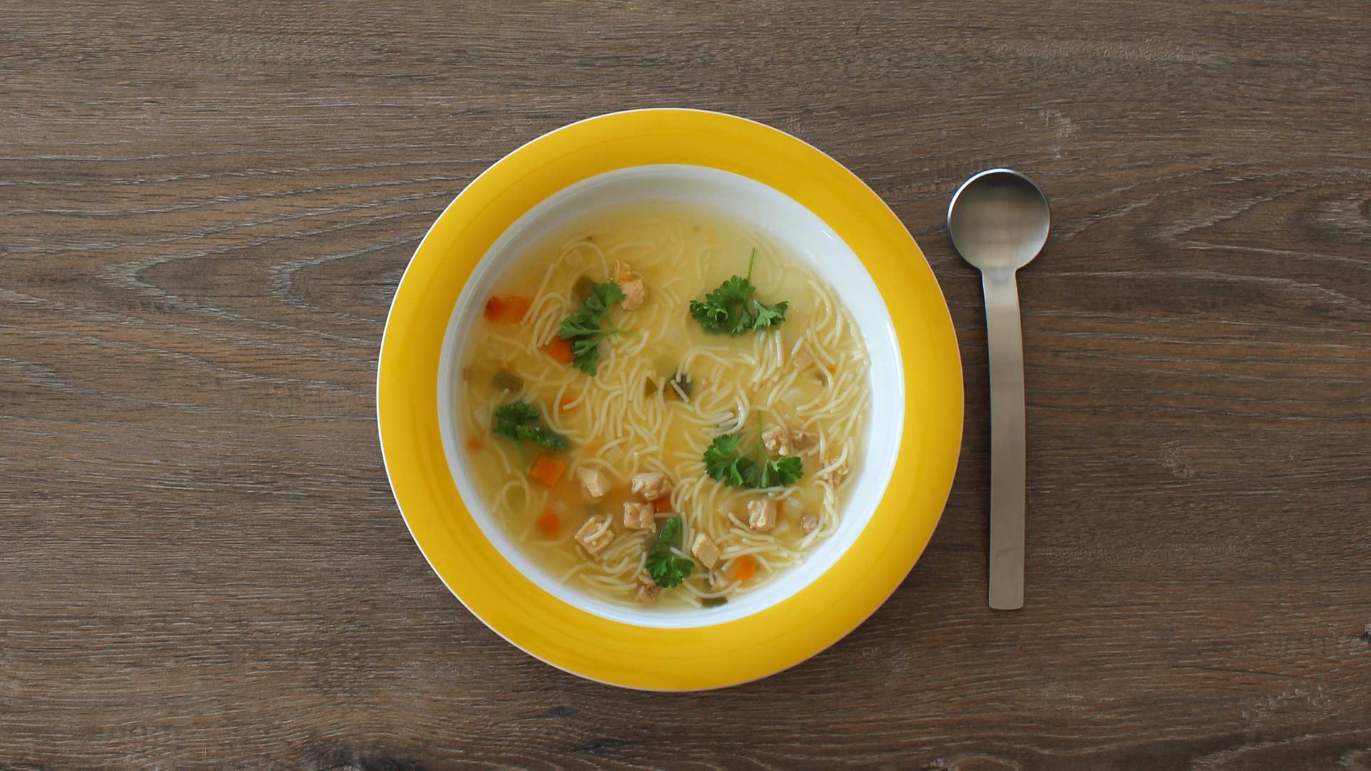 Teller mit Suppe mit Löffel