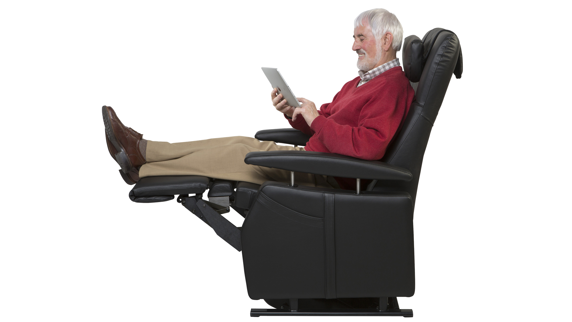 Ein Mann sitzt in einem Pflegesessel mit Fußstütze und liest.