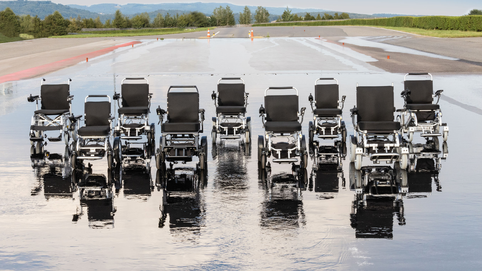 Eine Flotte von Elektrorollstühle FreedomChair auf einer Landebahn.