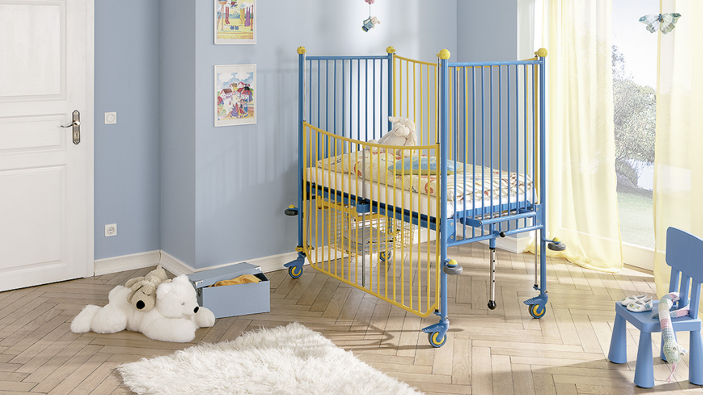 Für die rückenschonende Pflege hochgestelltes Kinderbett mit Gitterumrandung.
