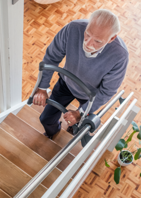 Ein älterer Mann hält sich beim Treppensteigen an einer Treppensteighilfe fest.