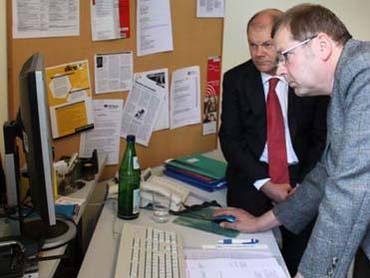 Olaf Scholz und Reinhard Giese (Vorstandsmitglied Barrierefrei Leben e.V.) probieren eine Greifhilfe aus.