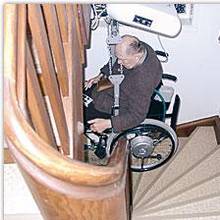 Beförderung eines Rollstuhlnutzers mit einem Treppendeckenlift (Hängelift) über eine enge Treppe.