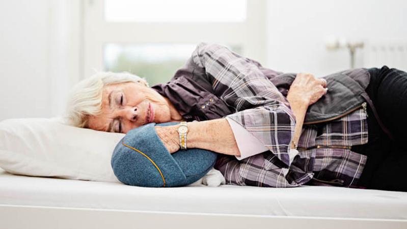 Ein älterer Mensch beim Ausprobieren eines Klangkissens im Bett.