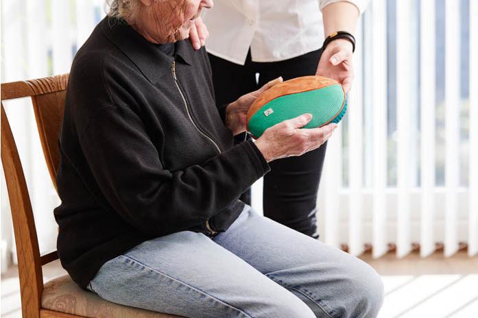 Ein älterer Mensch beim Ausprobieren eines Klangkissens.