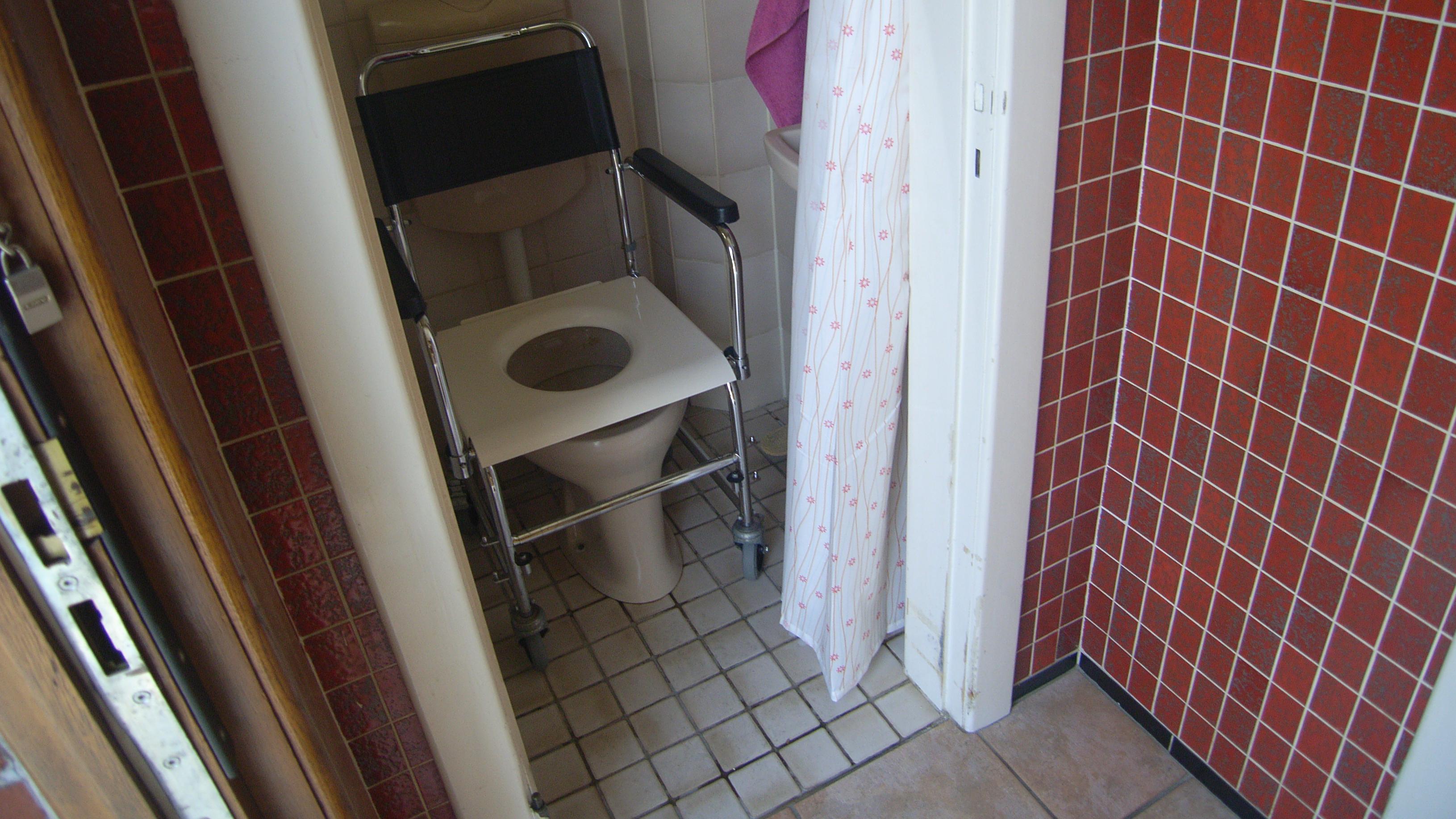 Ein Toilettenrollstuhl über dem WC-Becken geschoben.