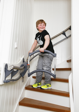 Ein Kind hält sich beim Treppensteigen an einer Treppensteighilfe fest.