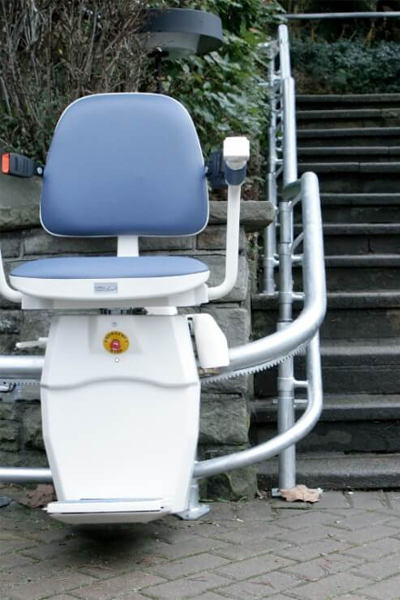 Wetterfester Treppenlift mit zwei Rohrschienenschienensystem an einer Treppe im Außenbereich.