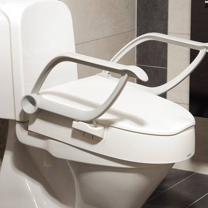 Ein Stand-WC mit einer Toilettensitzerhöhung mit beidseitigen Haltegriffen