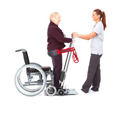 Ein Pflegeperson hilft einer Person mit Hilfe einer Transferhilfe aus dem Rollstuhl.