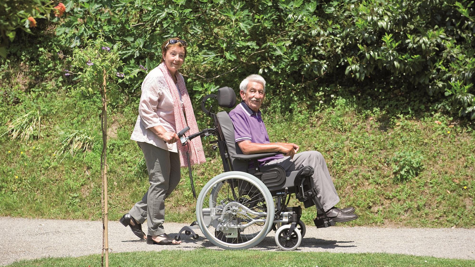 Ein im Rollstuhl sitzender Mann wird von einer Frau geschoben