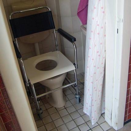 Ein Toilettenrollstuhl wurde über ein WC-Becken geschoben..