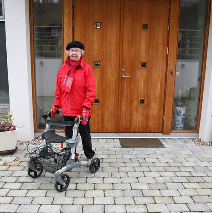 Eine Frau verlässt das Haus mit einem Rollator.