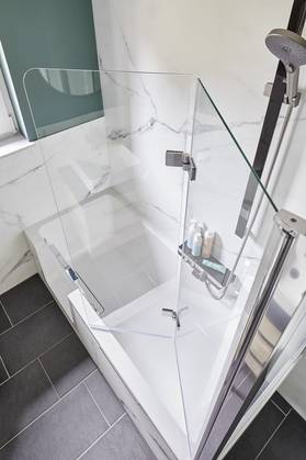 Kleines Bad mit einer Duschwanne mit Tür zum Duschen und zum Baden.