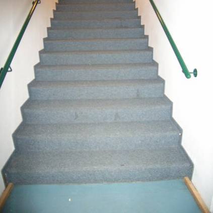 Kontrastreicher Übergang zur Treppe, die über einen beidseitigen Handlauf verfügt.