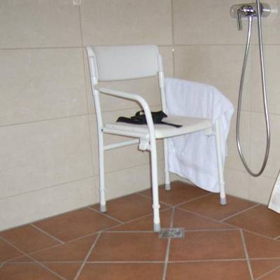 Duschstuhl mit Rückenlehne. Die Armlehnen erleichtern das Aufstehen/Hinsetzen und geben beim Duschen eine Sicherheit gegen seitliches Herunterfallen. Die Standbeine haben rutschhemmende Fußenden.