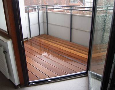 Blick von drinnen auf einen Balkon mit ähnlichen Niveau, wie der Boden im Inneren, sowie mit hohem Geländer.